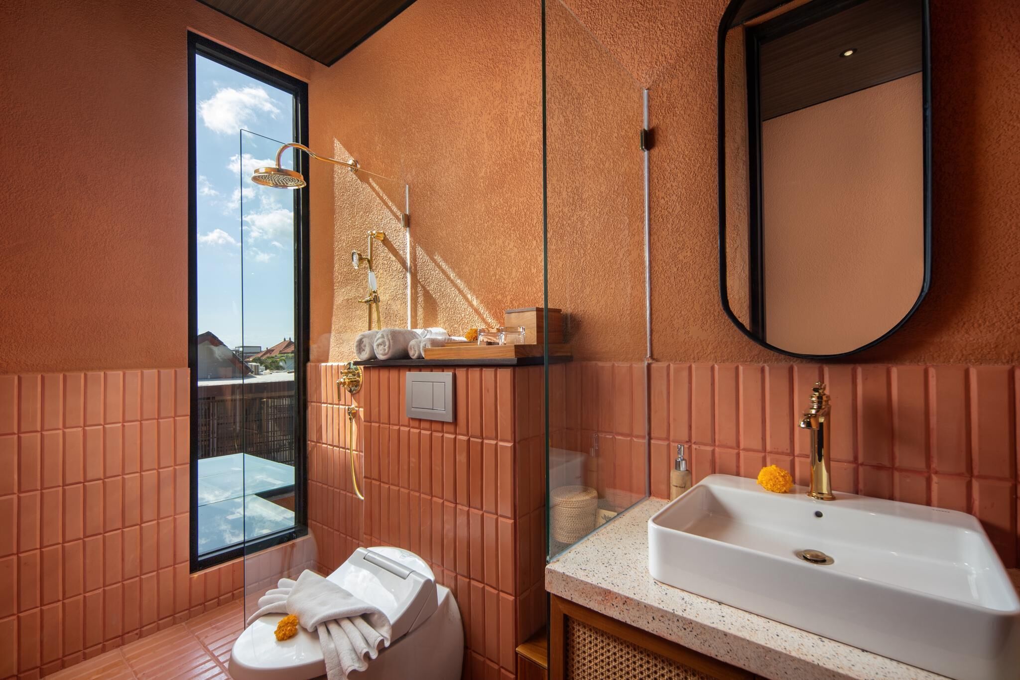 A bathroom with a large window, a white sink, and a mirror.
