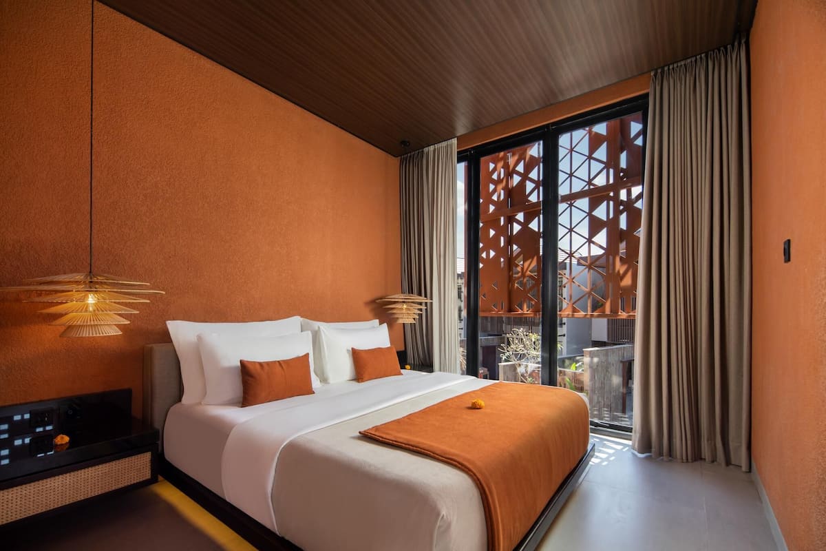 A hotel room with a large bed, a TV, and a balcony with a view.