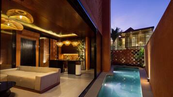 Un espacio exterior moderno con piscina, un sofá y una zona de bar.