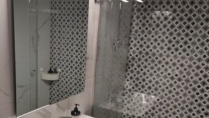 A bathroom with a white sink, a mirror, and a shower with a patterned wall. - Acropolis Oasis  (Athens)