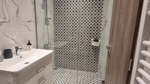 A modern bathroom with a marble vanity, a glass shower enclosure, and a patterned wall. - Acropolis Oasis  (Athens)