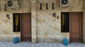 Vestíbulo de hotel con paredes de mármol, dos puertas con las indicaciones E3 y E2, unidades de aire acondicionado y cestas azules en el suelo.