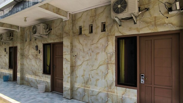 Fachada de edificio con paredes de mármol, varias unidades de aire acondicionado y una zona de entrada con baldosas.