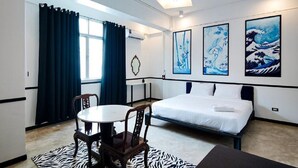 A modern hotel room with a bed, a dining table, and chairs. There are three framed artworks on the wall. - The Character Yaowarat (Bangkok)