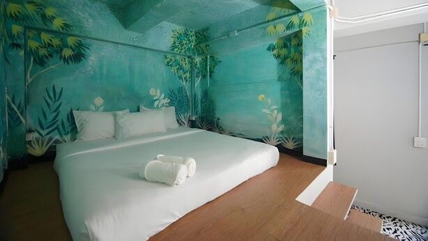 A bedroom with a bed, white bedding, and a tropical mural on the walls. - The Character Yaowarat (Bangkok)
