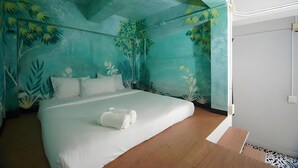 A bedroom with a bed, white bedding, and a tropical mural on the walls. - The Character Yaowarat (Bangkok)