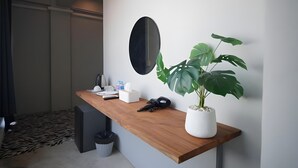 A modern room with a wooden desk, a potted plant, a mirror, and a trash bin. - The Character Yaowarat (Bangkok)