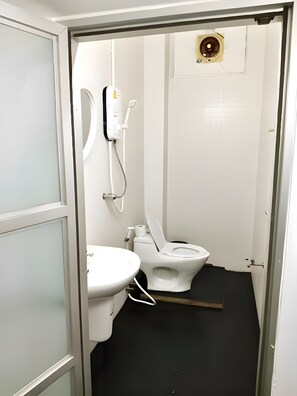 A small, compact bathroom with a toilet, a sink, and a shower unit. - The Character Yaowarat (Bangkok)