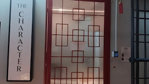 A wall with a framed sign that reads 'THE CHARACTER' and a decorative red panel with geometric patterns. - The Character Yaowarat (Bangkok)