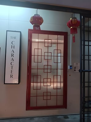 A wall with a framed sign that reads 'THE CHARACTER' and a decorative red panel with geometric patterns. - The Character Yaowarat (Bangkok)