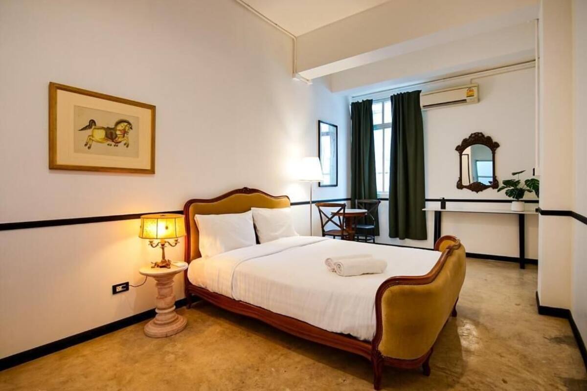 A hotel room with a bed, bedside table, lamp, and a framed picture on the wall.
