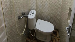 Een kleine betegelde badkamer met toilet en een muurkranen.