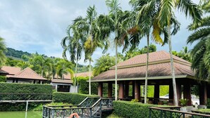 A resort with multiple bungalow-style buildings, a covered walkway, and a water body with a boat and life ring.