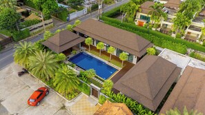 A residential area with a house featuring a swimming pool, surrounded by lush greenery and palm trees. - SeToVa Naiharn Grand Pool Villa, Rawai (Rawai)