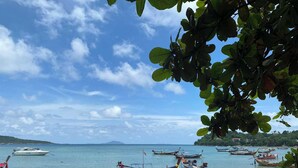 A beach with several boats anchored near the shore, a sandy beach, and a clear sky.