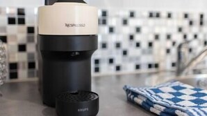 Une machine à café Nespresso avec un support à capsules de la marque Krups placé à côté.