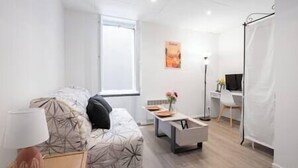 Un salon moderne et bien éclairé, avec un canapé, une table basse et un bureau équipé d’un ordinateur.