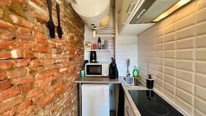 Une cuisine de taille réduite avec un mur en briques, un four à micro-ondes, un petit réfrigérateur et une cuisinière.