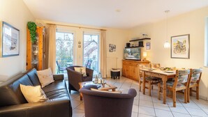 Een woonkamer met een bank, stoelen, een eettafel en een keukenhoek.