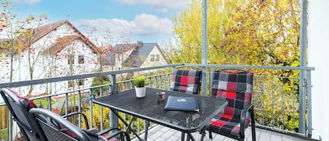 A balcony with a table and chairs, a laptop, and a potted plant.