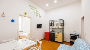 A compact living space with a kitchenette, a dining area, and a bed. - Casa Pulcinella a Spaccanapoli by Wonderful Italy (Naples)