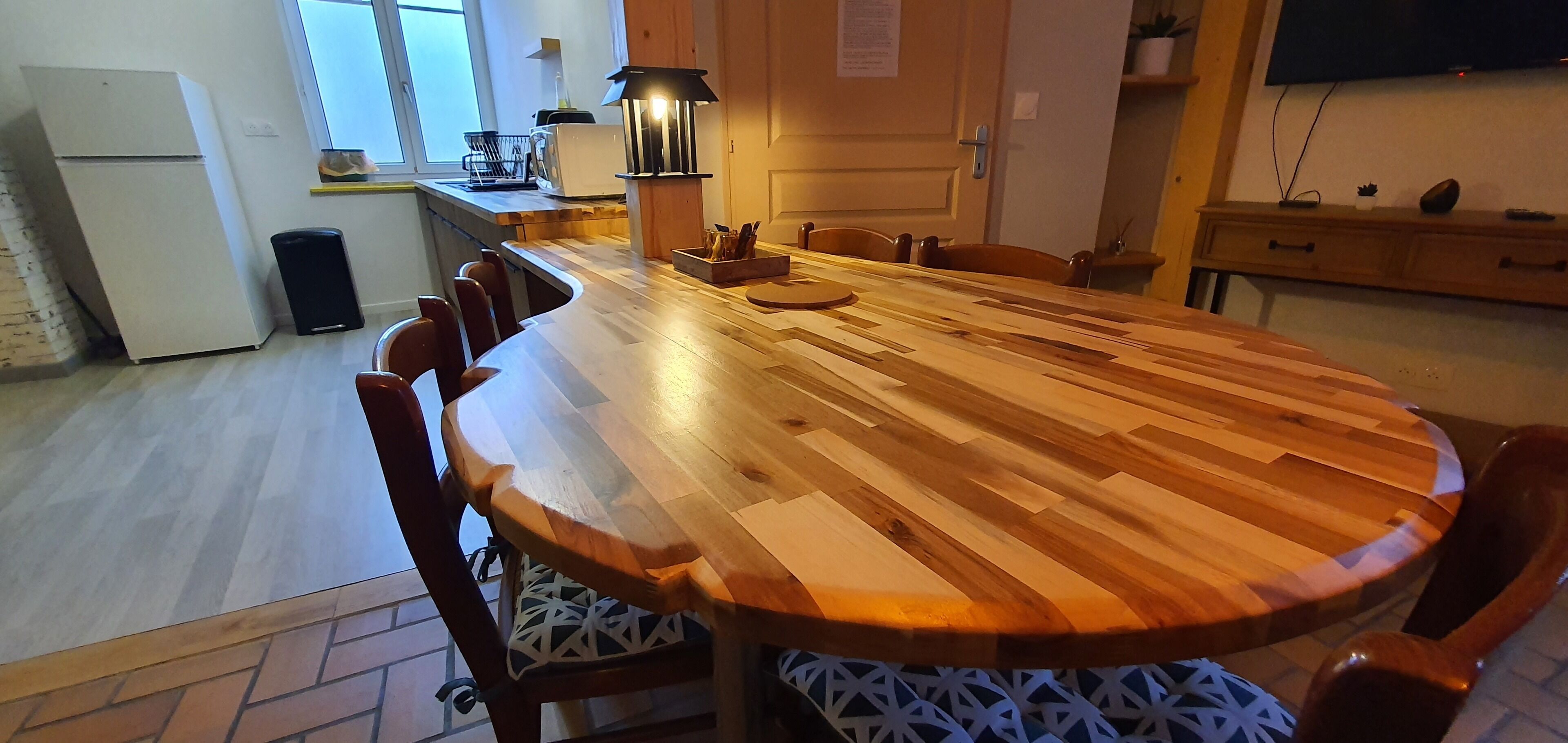 Une cuisine moderne avec une table à manger en bois, des chaises, un réfrigérateur, un évier et une cuisinière.