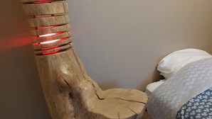 A wooden chair with red lights, a bed with patterned bedding, and a framed picture on the wall. - Cramiland - Appart 01 Ohnenheim (Ohnenheim)