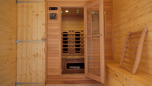 A wooden sauna room with a sliding door, a bench, and a sauna control panel. - Massane gîte for 2 to 8 people at Mas la Couloumine (Elne)