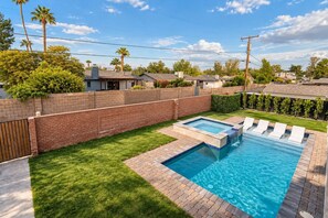 A backyard with a swimming pool, a brick wall, and a grassy lawn. - The Sundancer Oasis|Old Town|Pool+Spa|Rooftop Deck (Scottsdale)