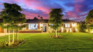 Una casa moderna con un prato curato, ampie finestre e un portone dotato di illuminazione.