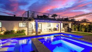 Una casa moderna con piscina, patio coperto e scala a chiocciola.