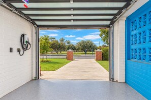 A garage entrance with a clear view of a suburban street, a blue garage door, and a solar panel on the wall. - The Sundancer Oasis|Old Town|Pool+Spa|Rooftop Deck (Scottsdale)