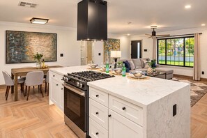 A modern kitchen with a central island, built-in oven, and a dining area with a table and chairs. - The Sundancer Oasis|Old Town|Pool+Spa|Rooftop Deck (Scottsdale)