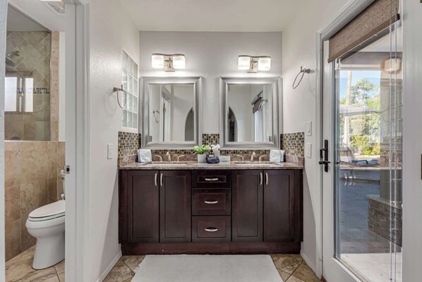 A modern bathroom with a double sink, dark wood cabinets, and a glass shower enclosure.