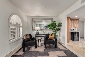 A modern living room with two black armchairs, a coffee table, a large mirror, and a potted plant.