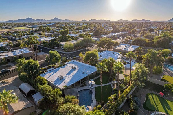 A residential area with houses, a swimming pool, and a mountain range in the background.