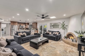 A modern living room with a fireplace, a dining area, and a kitchen.