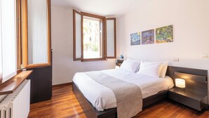 A bedroom with a bed, bedside table, lamp, and artwork on the wall. - Cozy flat for families in the city center with free parking, up to 5 people (Verona)