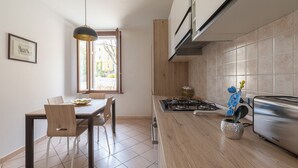A modern kitchen with a dining area, featuring a gas stove, a toaster, and a potted orchid. - Cozy flat for families in the city center with free parking, up to 5 people (Verona)