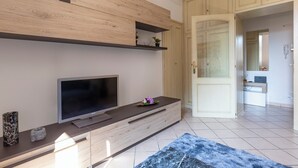 A modern living room with a flat-screen TV, wooden shelving, and a blue rug. - Cozy flat for families in the city center with free parking, up to 5 people (Verona)