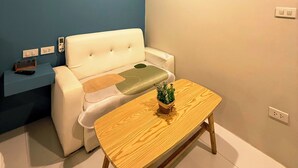 A modern living room with a white sofa, a wooden coffee table, and a blue accent wall. - THE NICE  (Patong)