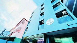 A modern building with multiple floors, a prominent sign for 'The Nice' hotel, and a visible storefront with a sign in a local language. - THE NICE  (Patong)