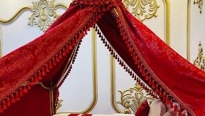 A luxurious bed with a canopy, ornate gold detailing on the headboard, and a red and white striped bedspread. - chateau le marara (Bwishyura)