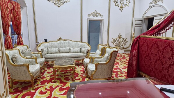 A luxurious room with a white sofa set, ornate gold detailing, and a red patterned carpet. - chateau le marara (Bwishyura)