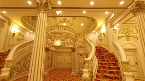 A grand staircase with ornate railings and a red carpeted floor leading to a door at the top. - chateau le marara (Bwishyura)