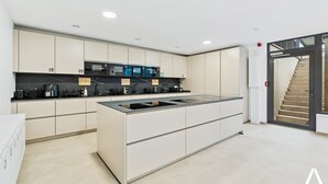 A modern kitchen with a central island, built-in appliances, and a staircase leading to an upper level.