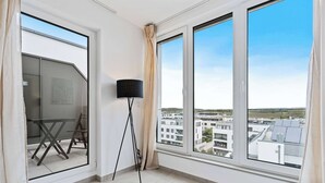 Una habitación con ventanas amplias, una lámpara de pie y vistas de la ciudad.