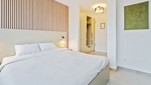 A modern bedroom with a large bed, a wooden slat wall, a closet, and a green abstract painting. - Bright & Cozy Coliving in Luxembourg (Luxembourg)