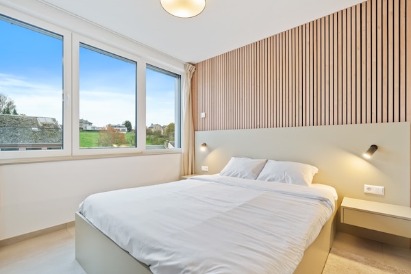 Inviting Living and Sleeping Space – Unwind in a cozy area featuring a queen-sized bed and a sophisticated wooden accent wall.
