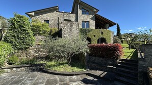 A stone building with a sloped roof, a chimney, and a small window.
